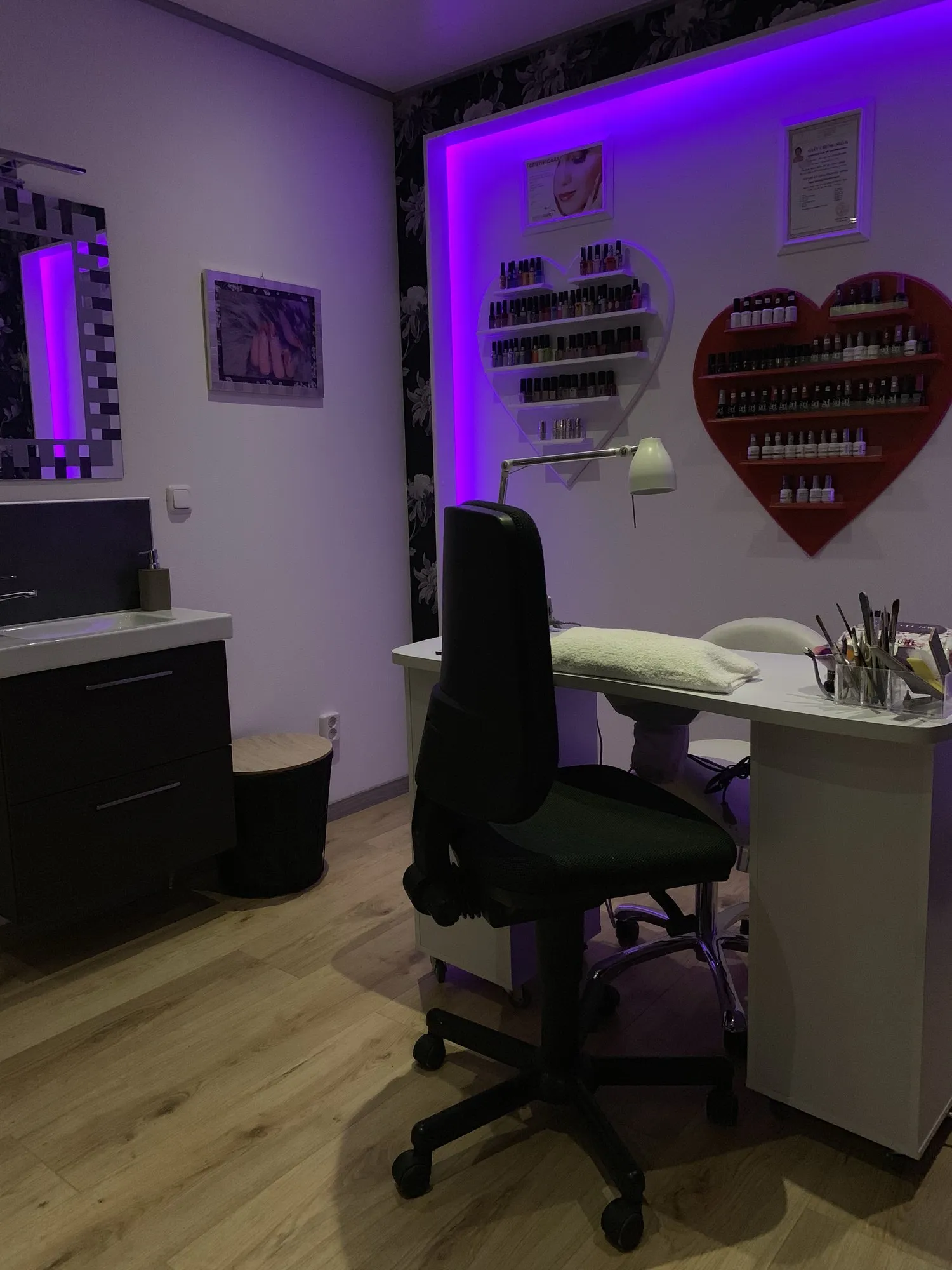 Overzicht van de studio met paarse verlichting, werktafel en nagellakrek in hartvorm