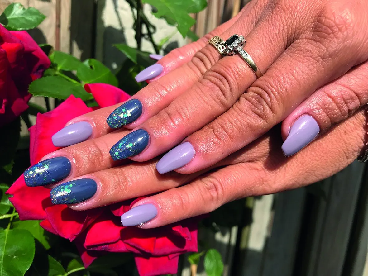 Blauwgrijze en lila nagels, gefotografeerd tussen rozen